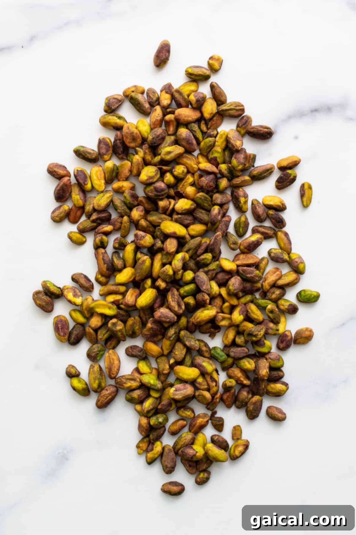 A scattering of raw, shelled pistachios on a kitchen counter, ready for roasting.