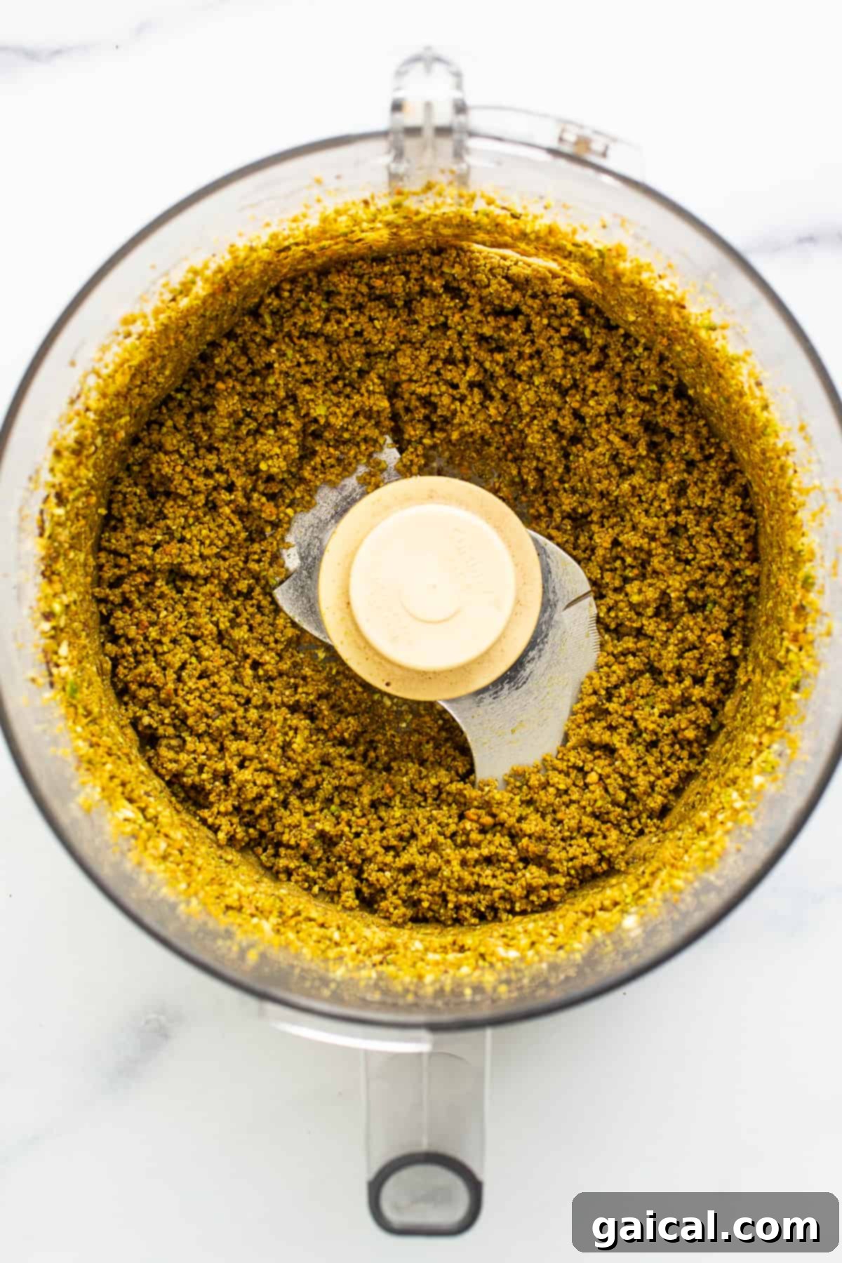 Pistachios being processed into a coarse meal in a food processor.