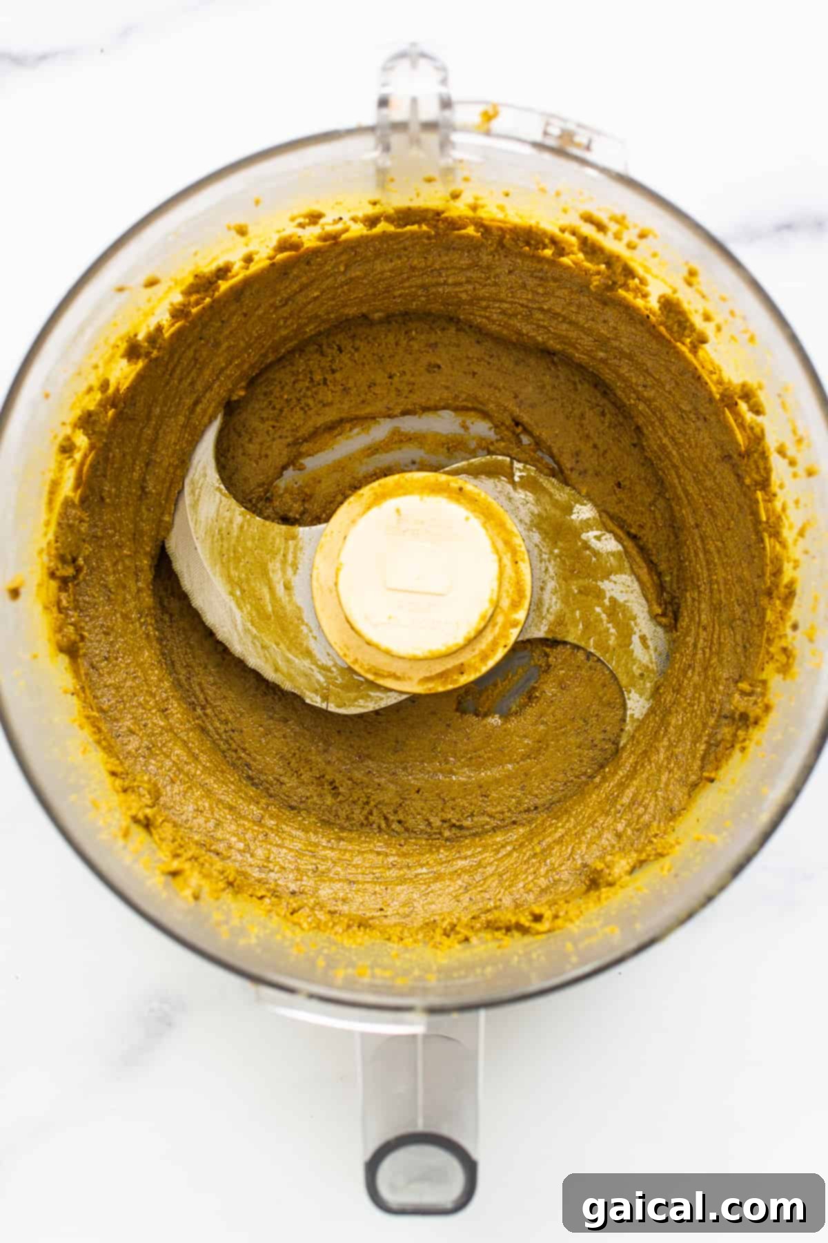 Smooth and creamy pistachio butter swirling in the food processor bowl.