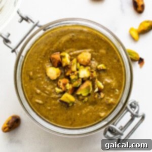 Pistachio nut butter in a glass container, perfectly smooth and vibrant green.