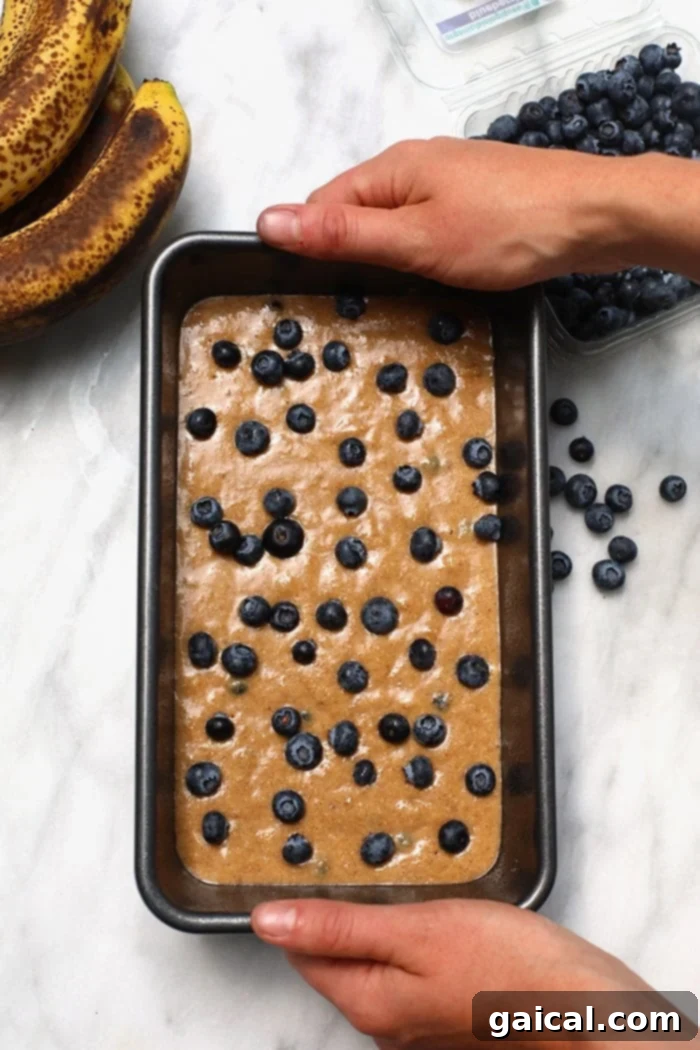 This healthy blueberry banana bread is an easy breakfast that the whole family will love! It is naturally sweetened, delicious and you just can’t beat moist banana bread. Make a loaf today! Thick, rich blueberry banana bread batter poured into a greased loaf pan, ready for baking.