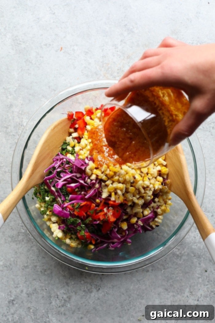 Colorful Veggies: The Heart of Your Fresh Corn Salad A large mixing bowl filled with the colorful raw ingredients of Thai Chili Summer Corn Salad, including freshly grilled corn kernels, vibrant carrot noodles, diced red pepper, and shredded purple cabbage, awaiting the dressing.