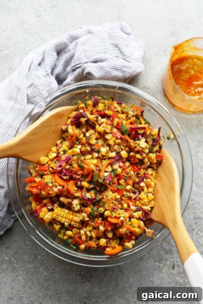 Thai Chili Corn Salad: The Ultimate Flavorful Summer Side Dish A large bowl of vibrant Thai Chili Corn Salad served as a side dish, accompanied by grilled sausage links and a bowl of crispy tortilla chips on a rustic wooden table, suggesting a perfect casual meal.