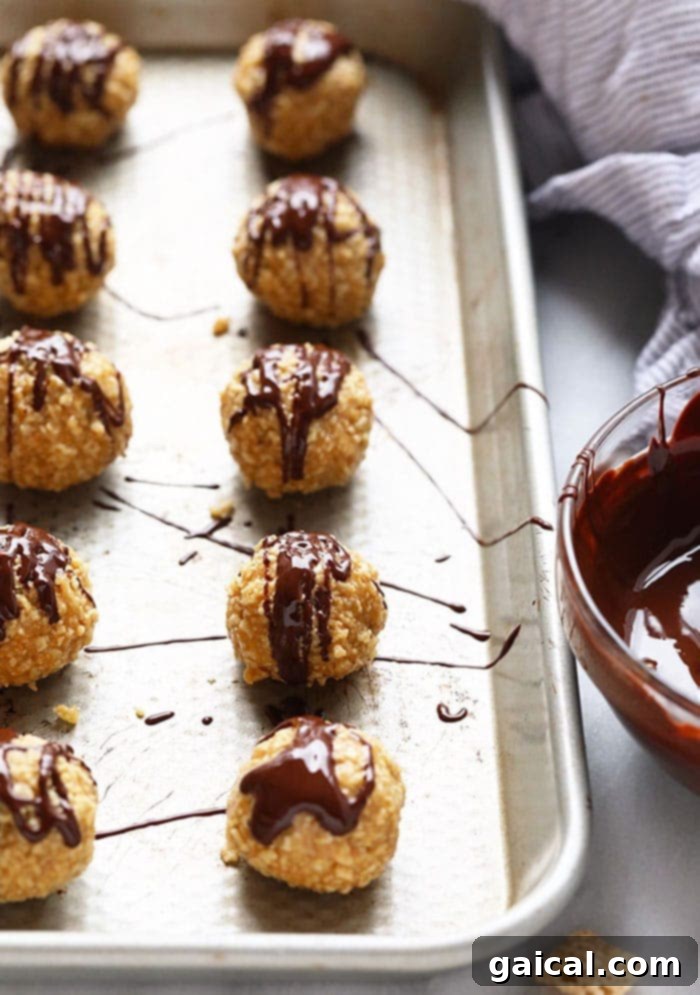 A tray of chocolate-covered peanut butter balls elegantly arranged on a baking sheet, showcasing their delicious coating.