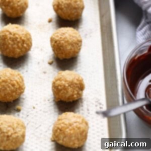 Granola bites on a baking sheet with a bowl of dipping sauce, showing the no-bake peanut butter balls ready for chilling.