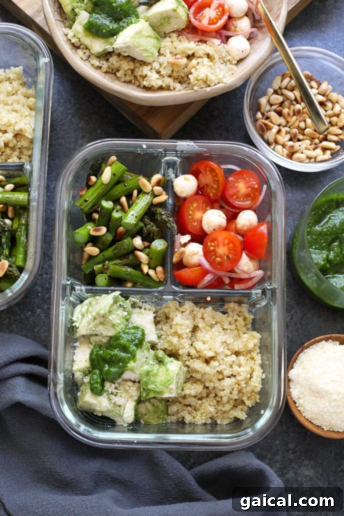 Pesto chicken, roasted asparagus, quinoa, and mozzarella-tomato salad neatly arranged in a meal prep container for a healthy, ready-to-eat lunch.