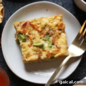 A plate with a piece of quiche and a fork.