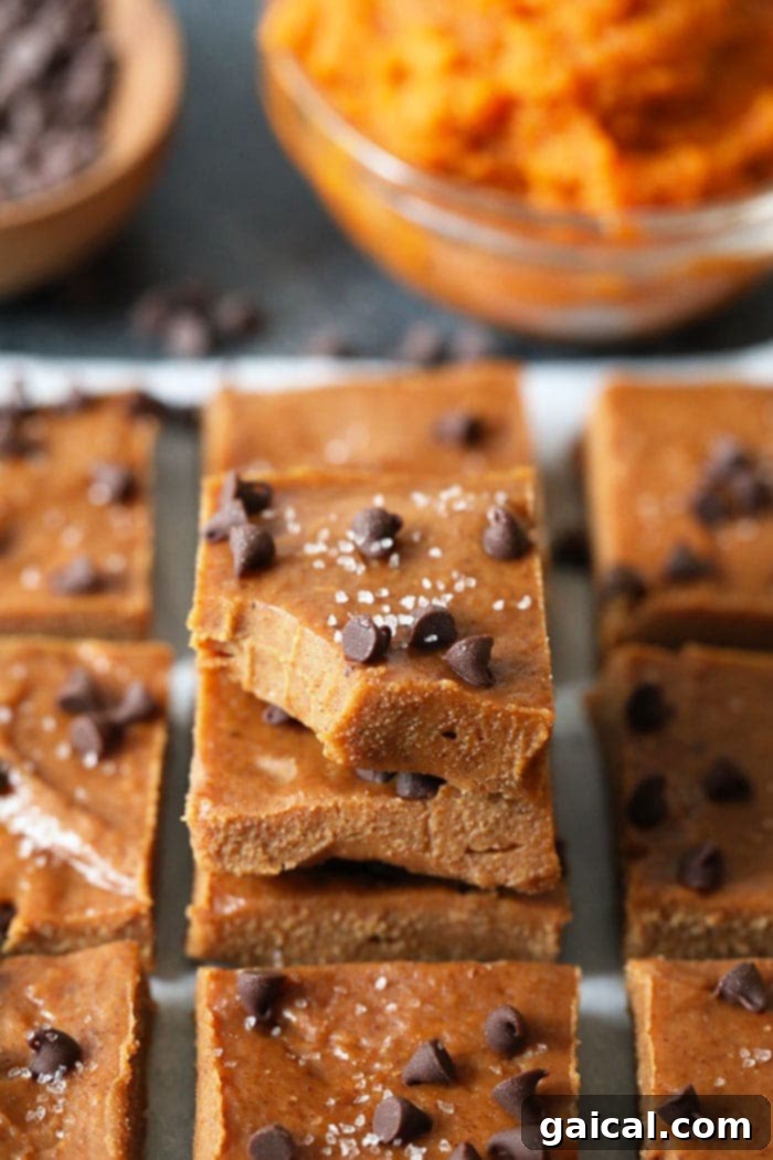 Perfectly sliced squares of vibrant pumpkin almond butter freezer fudge arranged beautifully on a rustic wooden board, ready to be served and enjoyed.