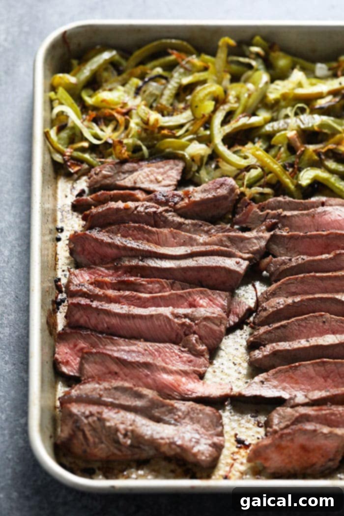 Four meal prep bowls neatly organized, each containing components of the Philly cheesesteak: steak, veggies, rice, and kale.