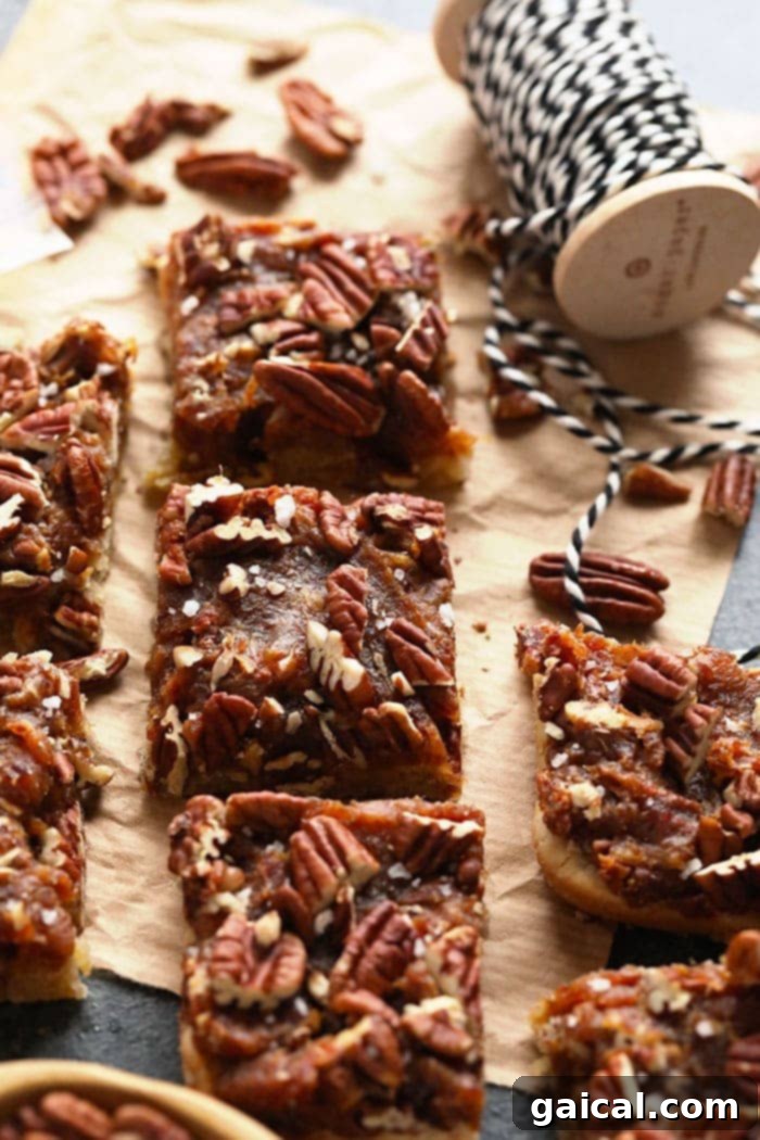 Healthy Pecan Pie Bars with Date Caramel and Almond Crust Finished healthy pecan pie bars stacked on a plate, showcasing the almond crust and date caramel filling with pecans.