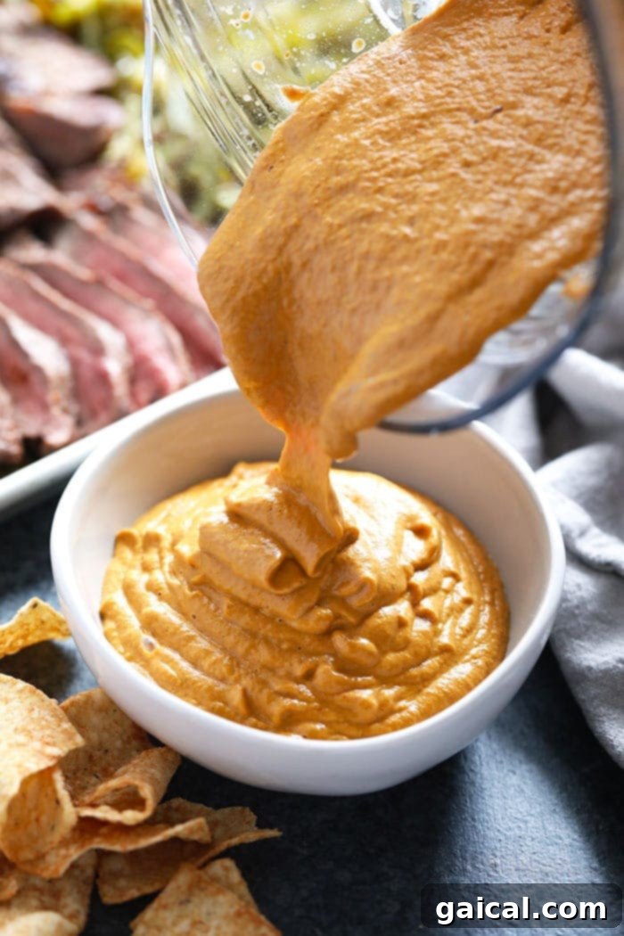 Smooth vegan queso being poured into a serving bowl.