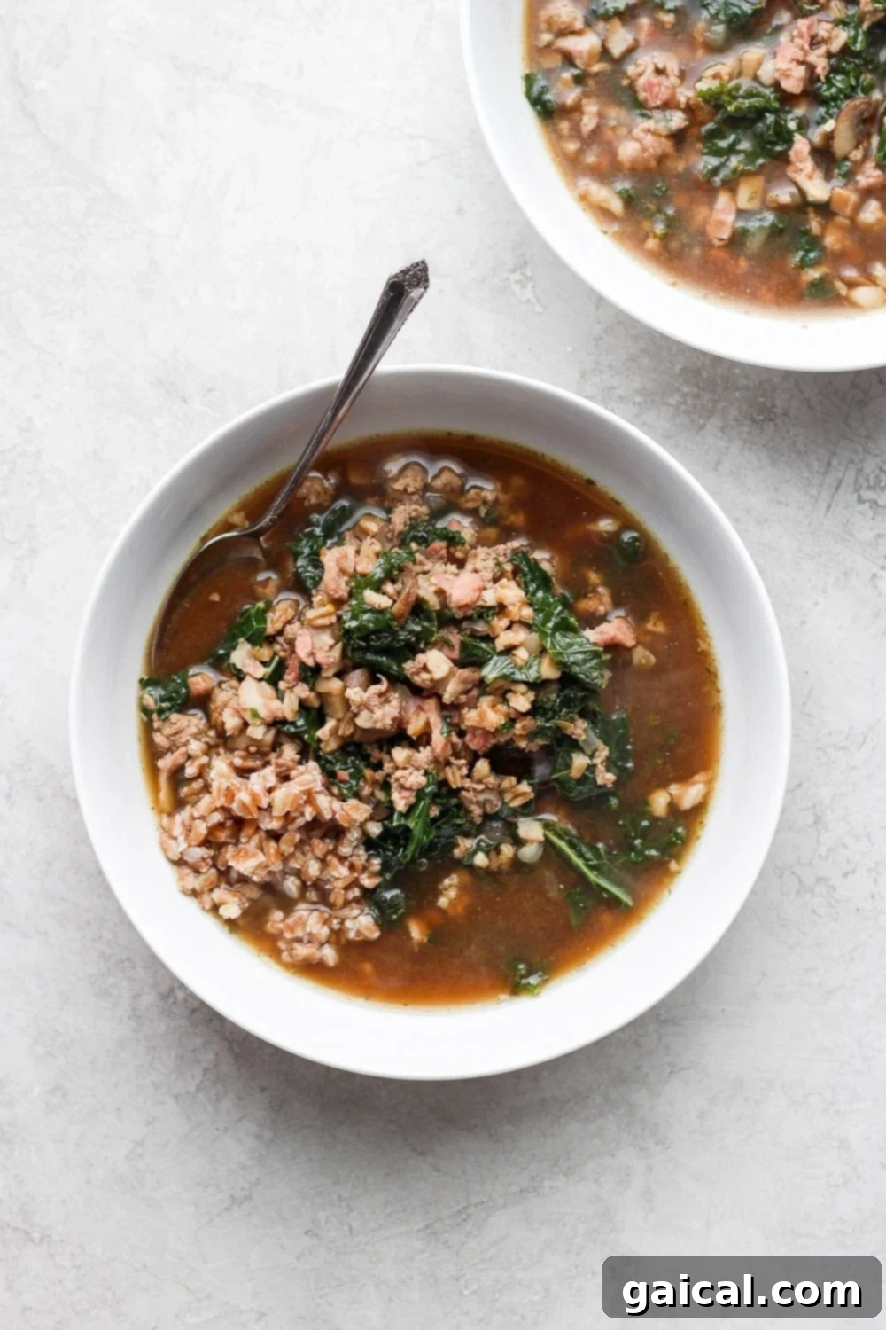 A large bowl of hearty ground turkey farro soup with fresh kale, ready to be served.