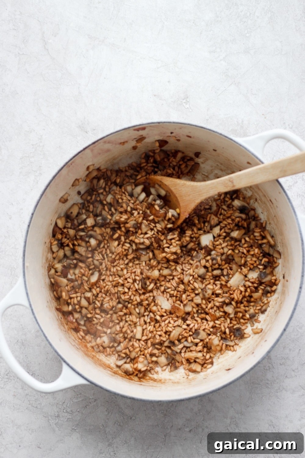 Farro, mushrooms, and other aromatics cooking together in a large Dutch oven, building layers of flavor for the soup.