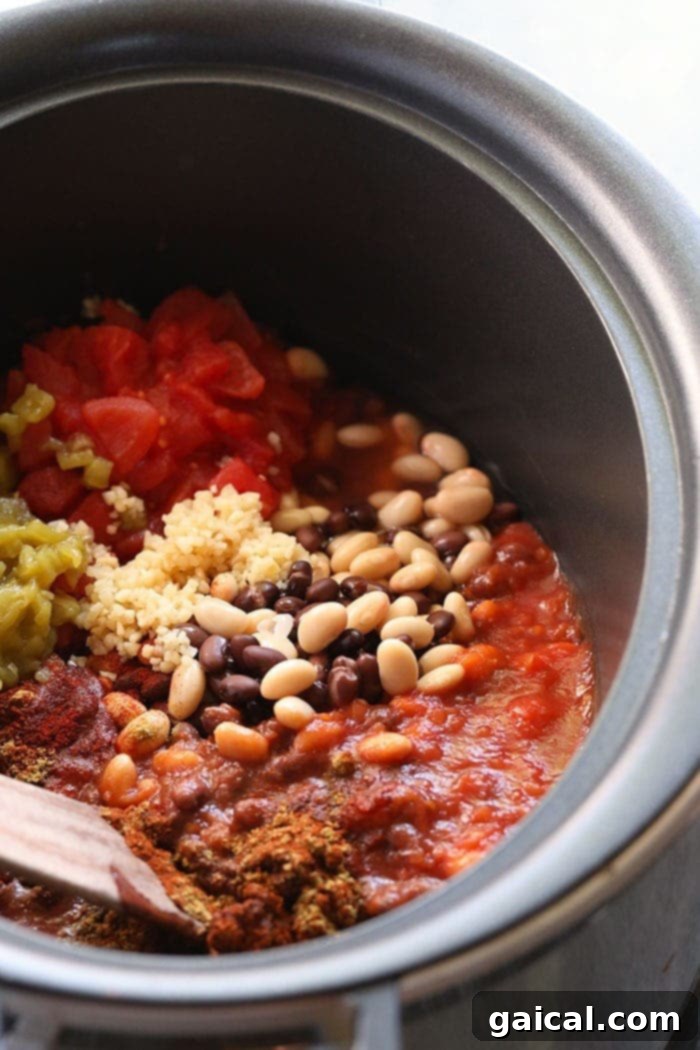 Slow Cooker Chicken Chili: Effortless cooking for a comforting meal. Close-up of chicken chili simmering in a red crockpot, with a ladle resting inside, showcasing the rich texture and colorful ingredients.