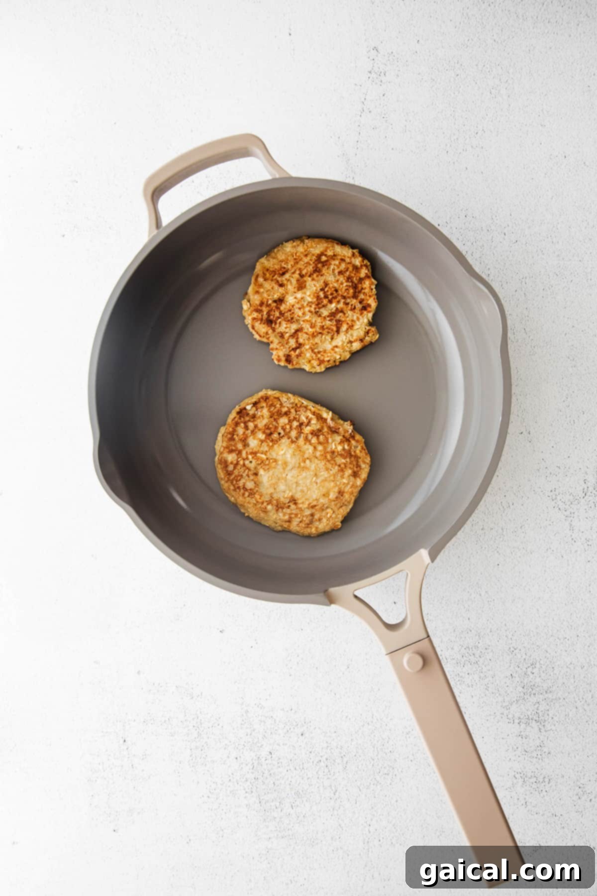 Cooking several banana oatmeal pancakes on a hot skillet, showing their golden-brown edges.