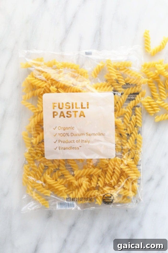 Close-up of uncooked fusilli pasta in a rustic bowl, highlighting its spiral shape perfect for holding creamy sauces in a vegan pasta bake.