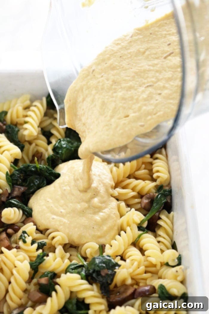 Creamy vegan pasta bake with a rich white wine cashew sauce filling a ceramic casserole dish, ready to be placed in the oven for baking until golden and bubbling.