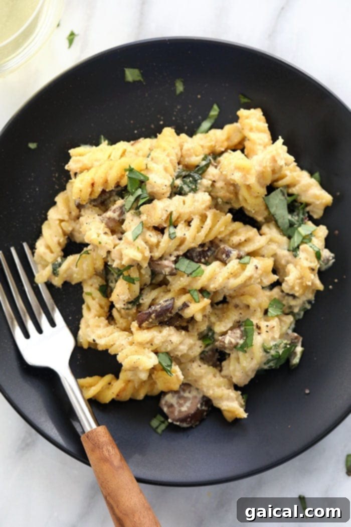 A single serving of creamy vegan pasta bake with white wine cashew sauce in a cozy white bowl, garnished with fresh basil, ready for a delicious meal.