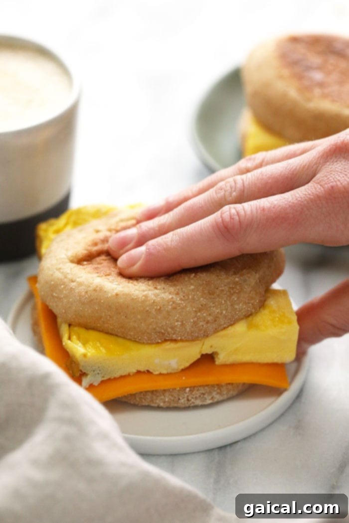 A basic breakfast sandwich with egg and cheese on an English muffin, served on a plate.