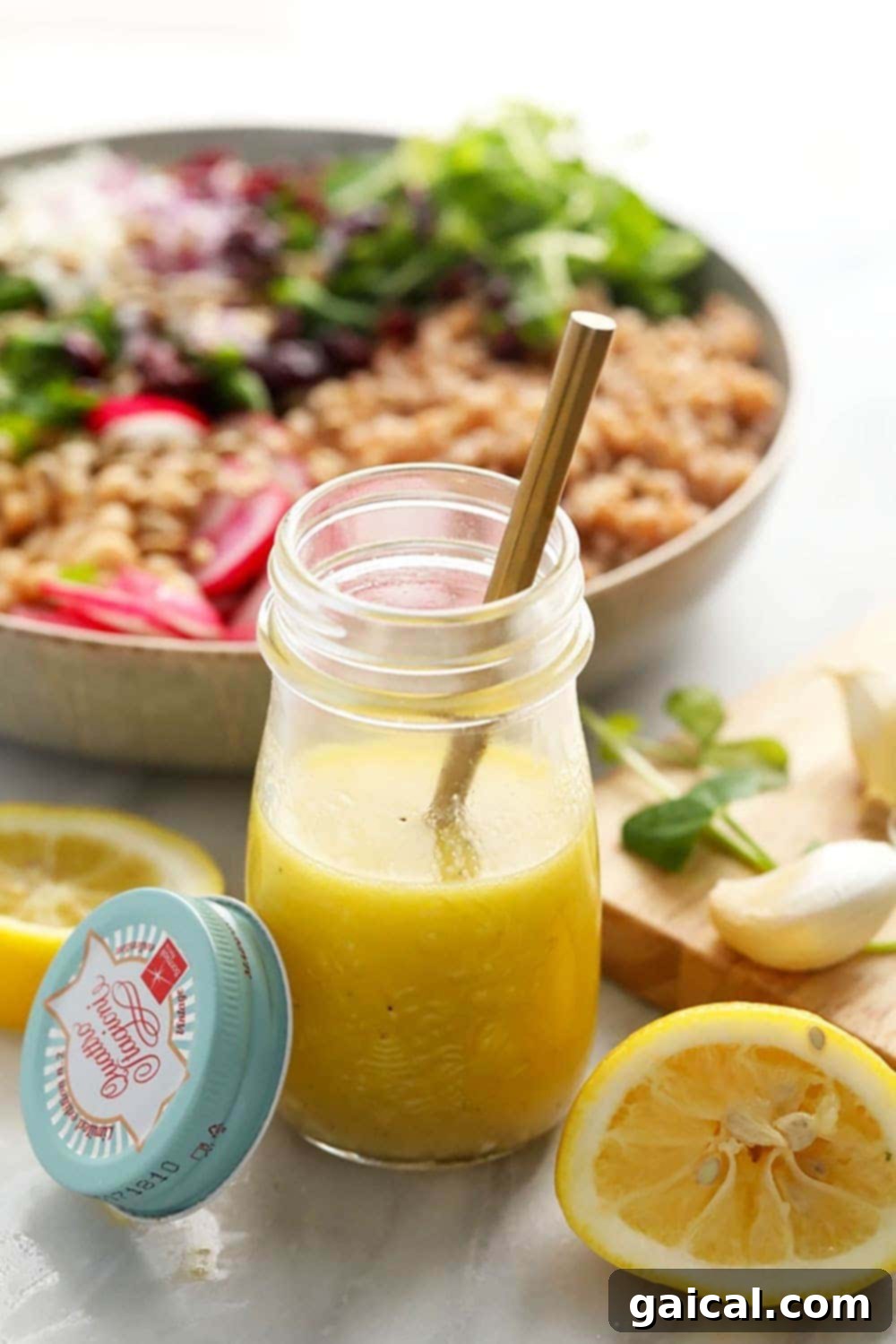 Lemon vinaigrette A glass jar containing a bright yellow lemon vinaigrette dressing, with fresh lemon slices in the background.