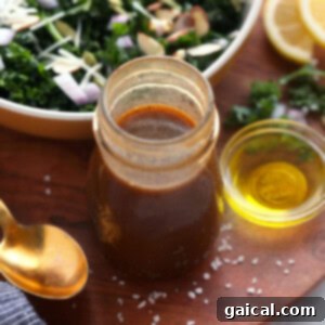 Elevate Your Greens: 12 Unforgettable Salad Dressings 2 A homemade kale salad with a jar of balsamic vinaigrette dressing on the side.