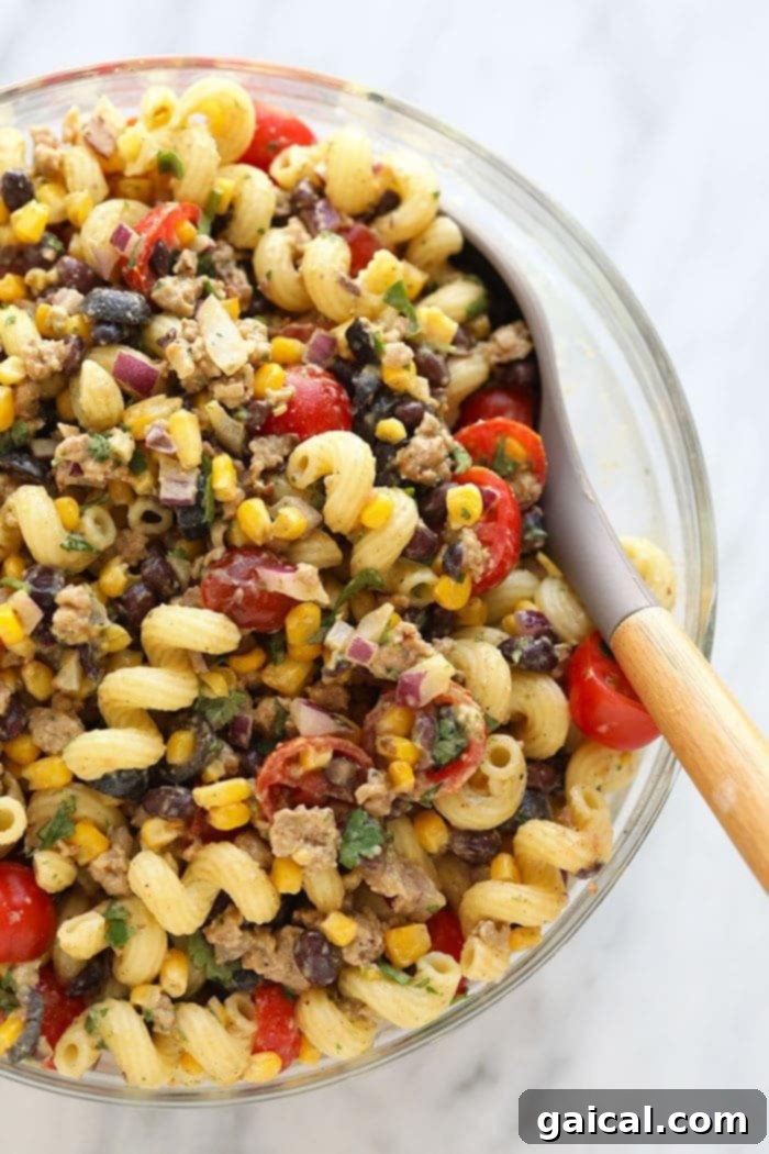 Our taco pasta salad is a fusion between beef tacos and pasta salad, leaving you with a hearty meal or side that the whole family will love. Large bowl filled with vibrant taco pasta salad, ready for serving