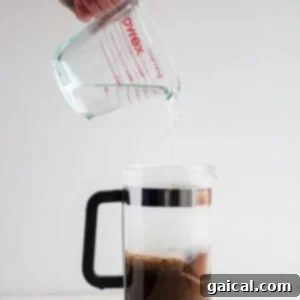 Mastering the French Press 10 A person carefully pouring hot water into a French press, initiating the brewing process.