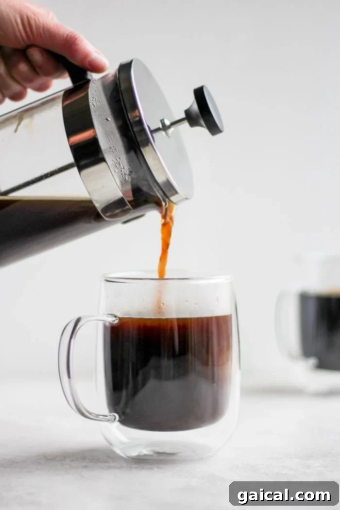 Mastering the French Press 3 Pouring freshly brewed French press coffee into a mug, steam gently rising.
