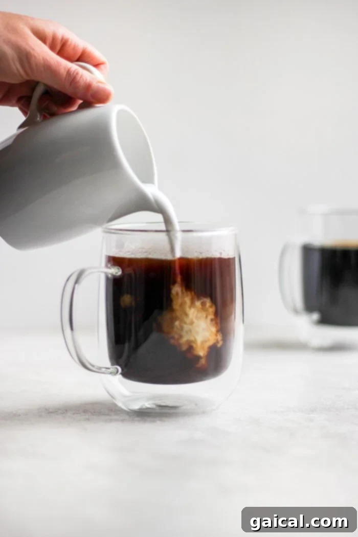 Mastering the French Press 7 A stream of cream being poured into a dark cup of coffee, creating beautiful swirls.