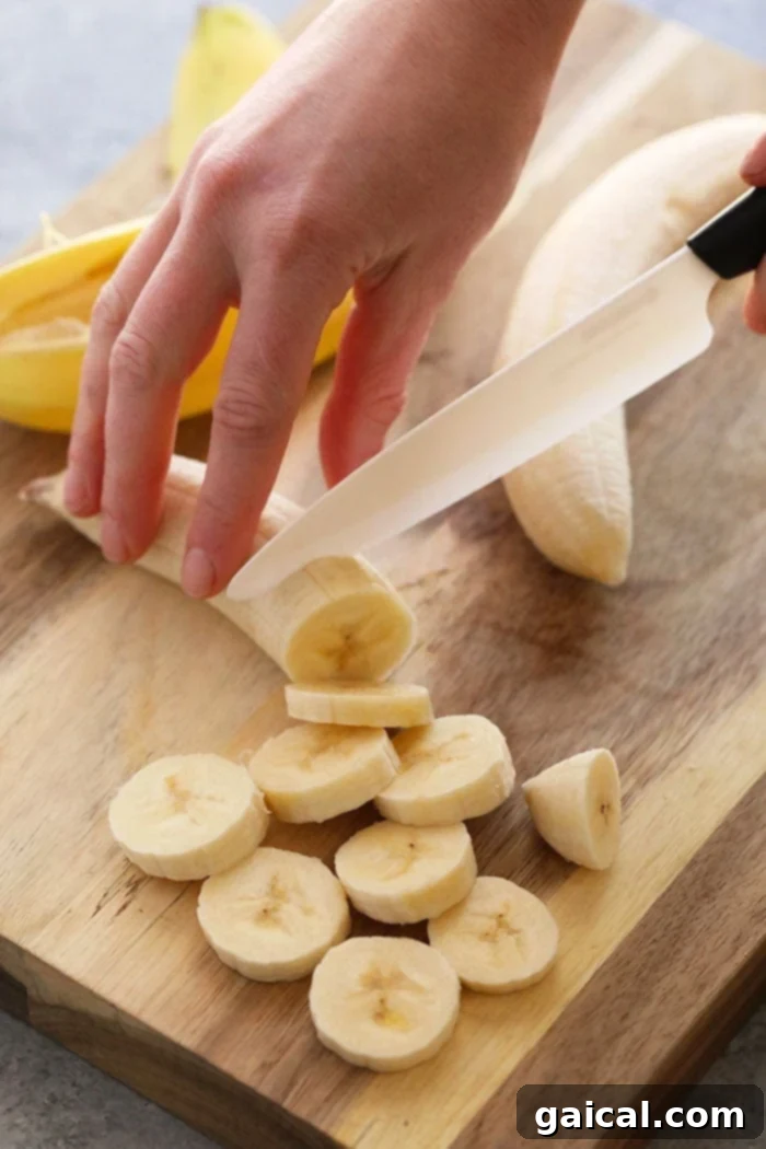 Slicing Bananas for Freezing Slicing ripe bananas on a wooden cutting board, preparing them for the freezing process