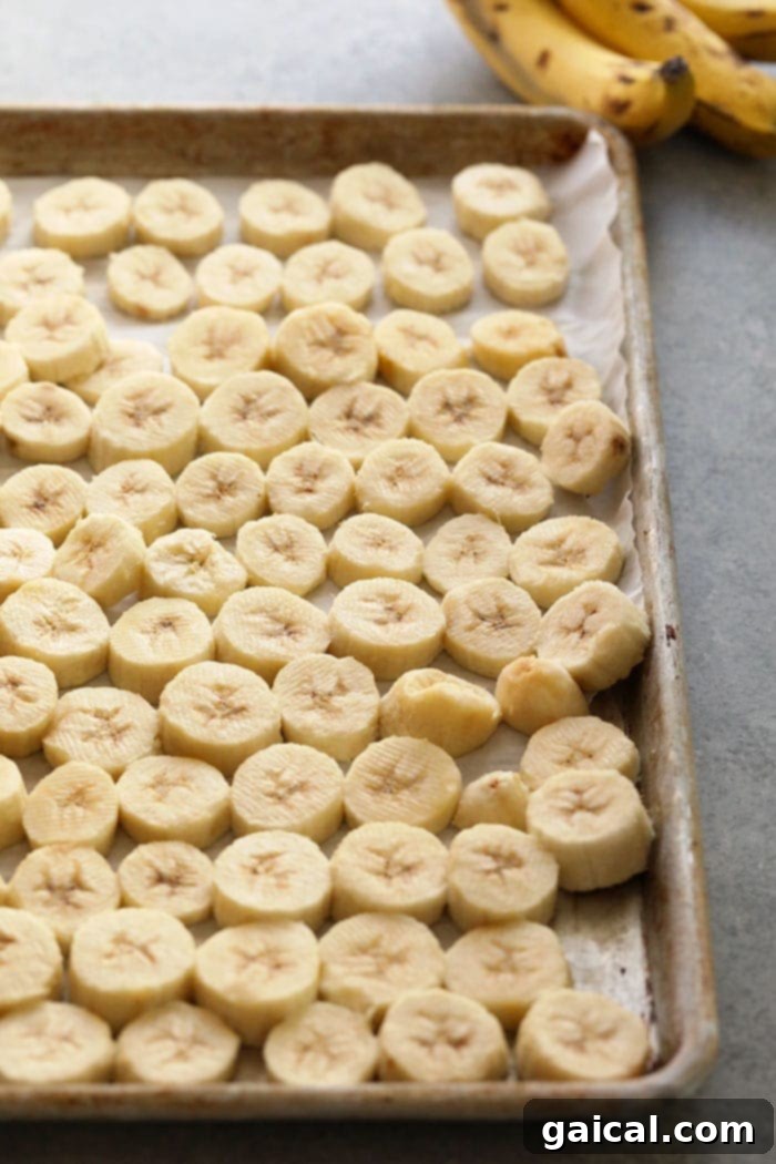 Bananas Arranged on Baking Sheet Neatly arranged banana slices on a parchment-lined baking sheet, ready for the freezer