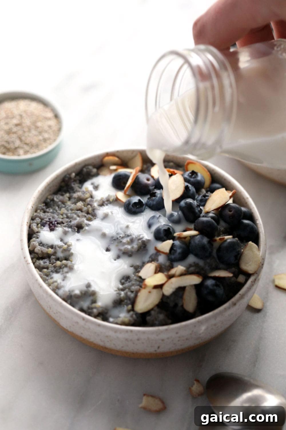 Wholesome Blueberry Quinoa Morning Bowl 4 Pouring almond milk over blueberry breakfast quinoa.