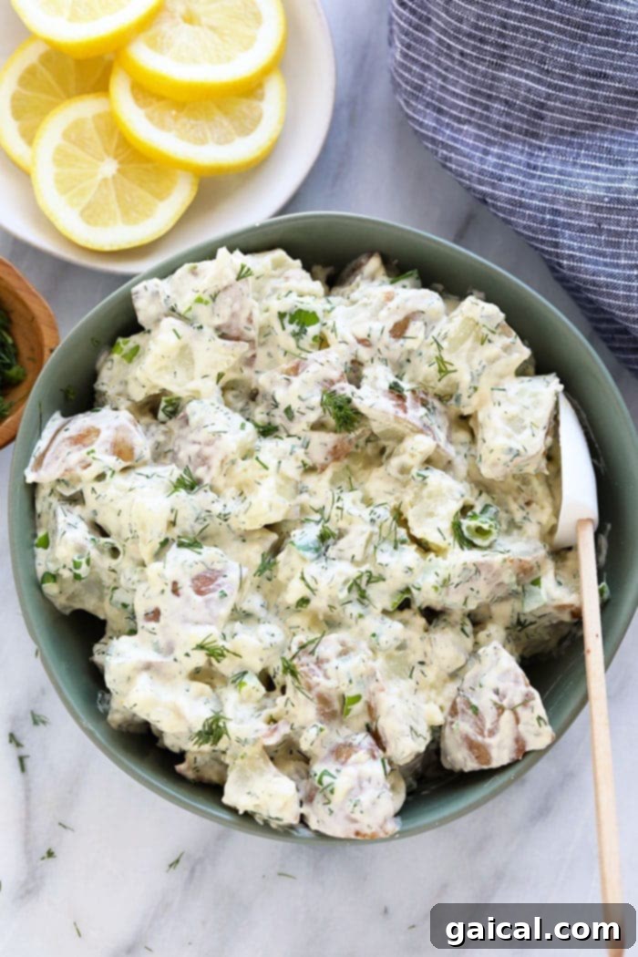 A beautifully presented bowl of creamy vegan potato salad, garnished with fresh dill sprigs, ready for serving at a summer gathering.