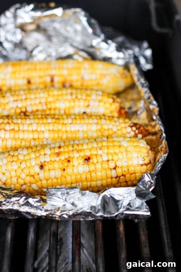 Fresh off the grill Mexican Street Corn is the absolute best. We've got a super simple Grilled Mexican Street Corn recipe that will make your tastebuds dance and your tummy asking for seconds! corn in tin foil on grill.