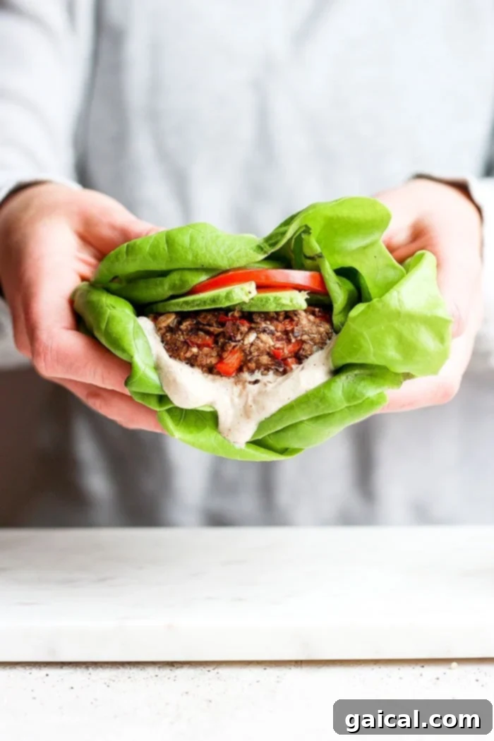 A vibrant black bean quinoa burger elegantly presented in crisp butter lettuce wraps.