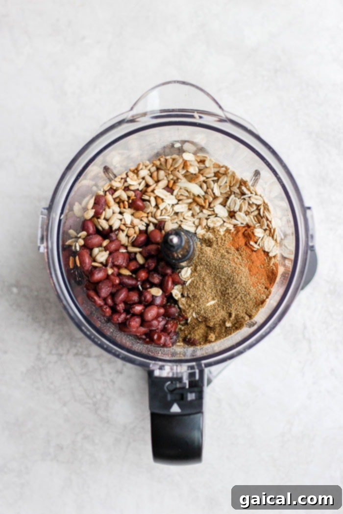 Black beans, sunflower seeds, oats, and spices being processed in a food processor, creating the binder for the burgers.