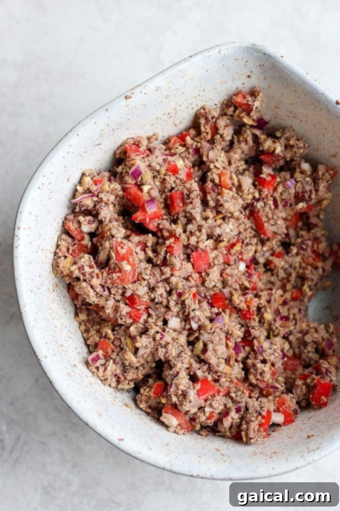 The combined black bean burger mixture in a bowl, showing visible pieces of quinoa, bell pepper, and onion.