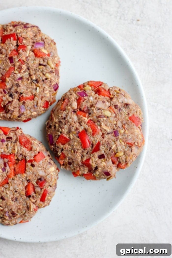 Several perfectly formed black bean quinoa burgers arranged neatly on a plate, ready for baking.