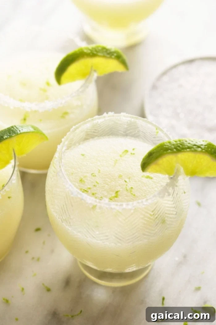 Delicious frozen margaritas, perfectly blended and garnished with lime, ideal for summer gatherings. Two glasses of frosty frozen margaritas, garnished with fresh lime wedges, ready to be enjoyed.