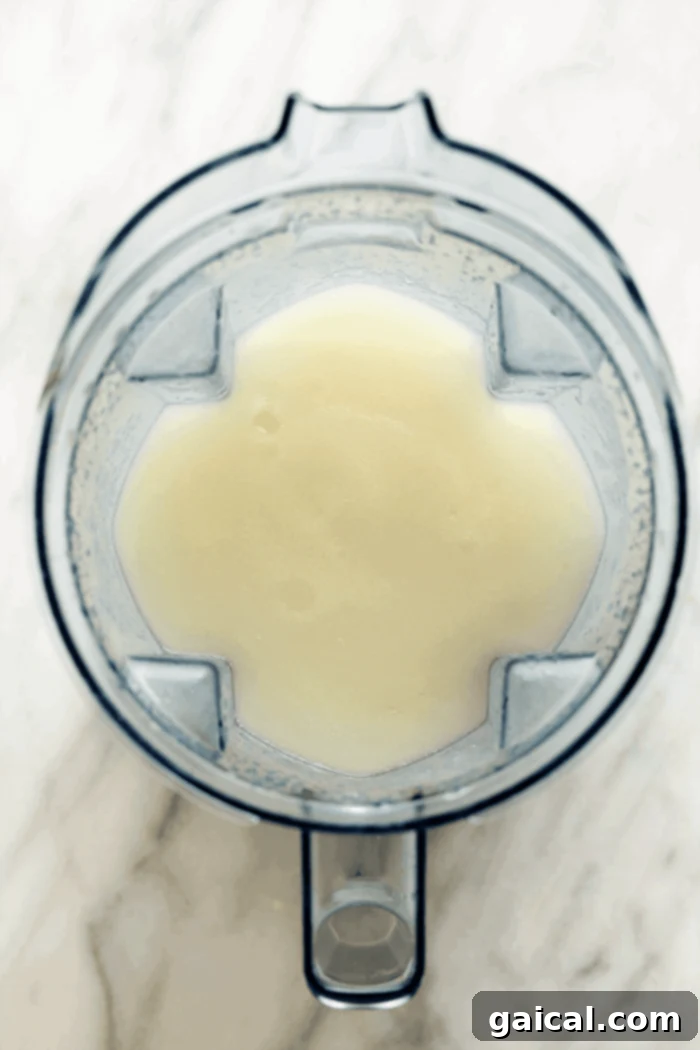 Watch your margarita ingredients transform into a perfect frozen blend in a high-speed blender. Tequila, lime juice, orange liqueur, agave, and ice being blended into a frozen margarita inside a Vitamix blender, creating a smooth, icy texture.