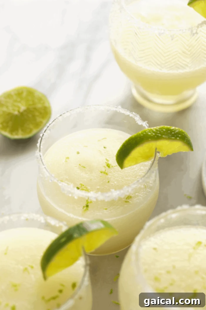Enjoy this delightful frozen margarita, perfectly balanced and refreshing. A single frozen margarita in a classic glass, garnished with a vibrant green lime slice, resting on a white surface, ready for enjoyment.