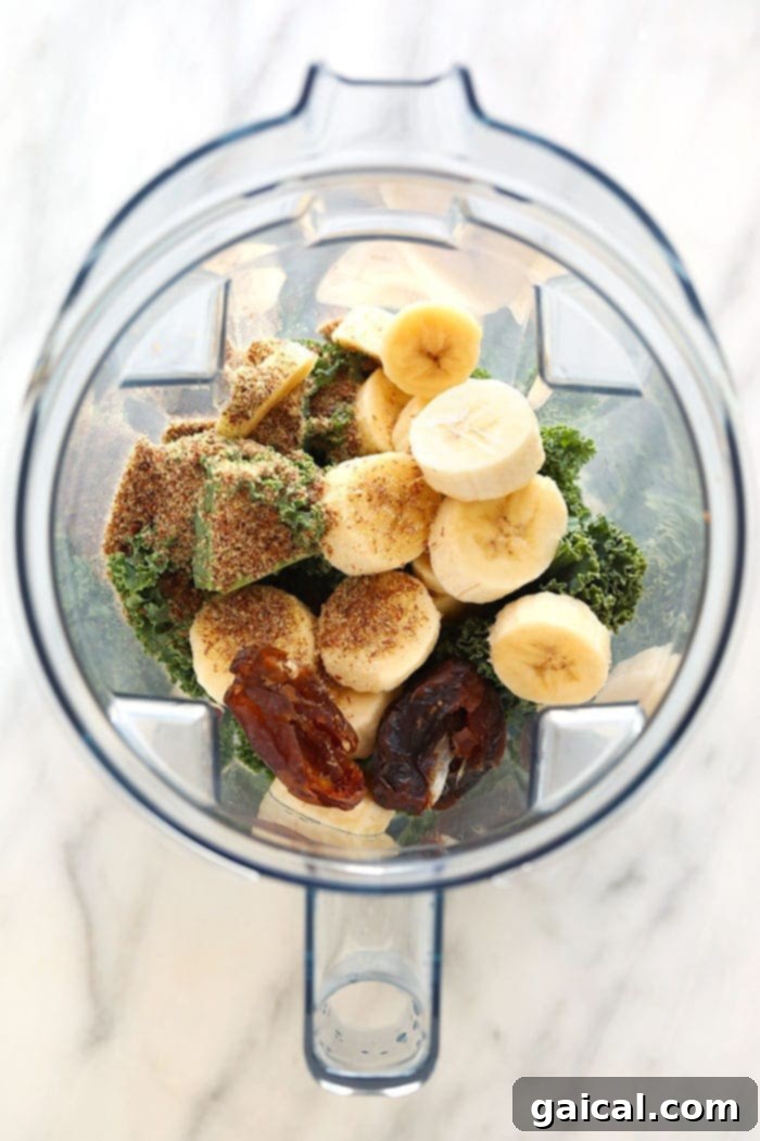 Get your daily greens here! This is the most delicious kale smoothie you'll ever make! It's packed with nutrient dense kale, frozen bananas and the perfect flavor punch of orange juice and fresh ginger. Whip up this green smoothie in 5 minutes and you're off and running with a healthy breakfast or snack on the go. Fresh ingredients for a kale smoothie, including kale, frozen bananas, dates, and orange juice, ready to be blended.