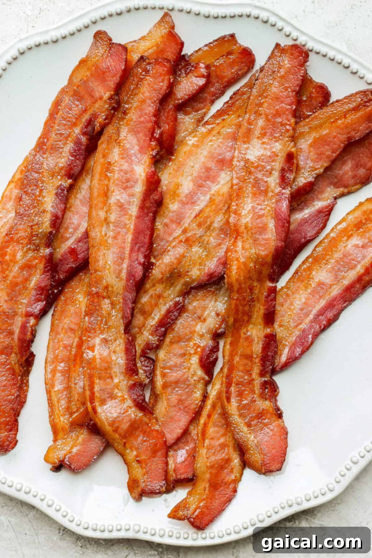 Mastering Crispy Oven Bacon 2 bacon on a plate on a table.