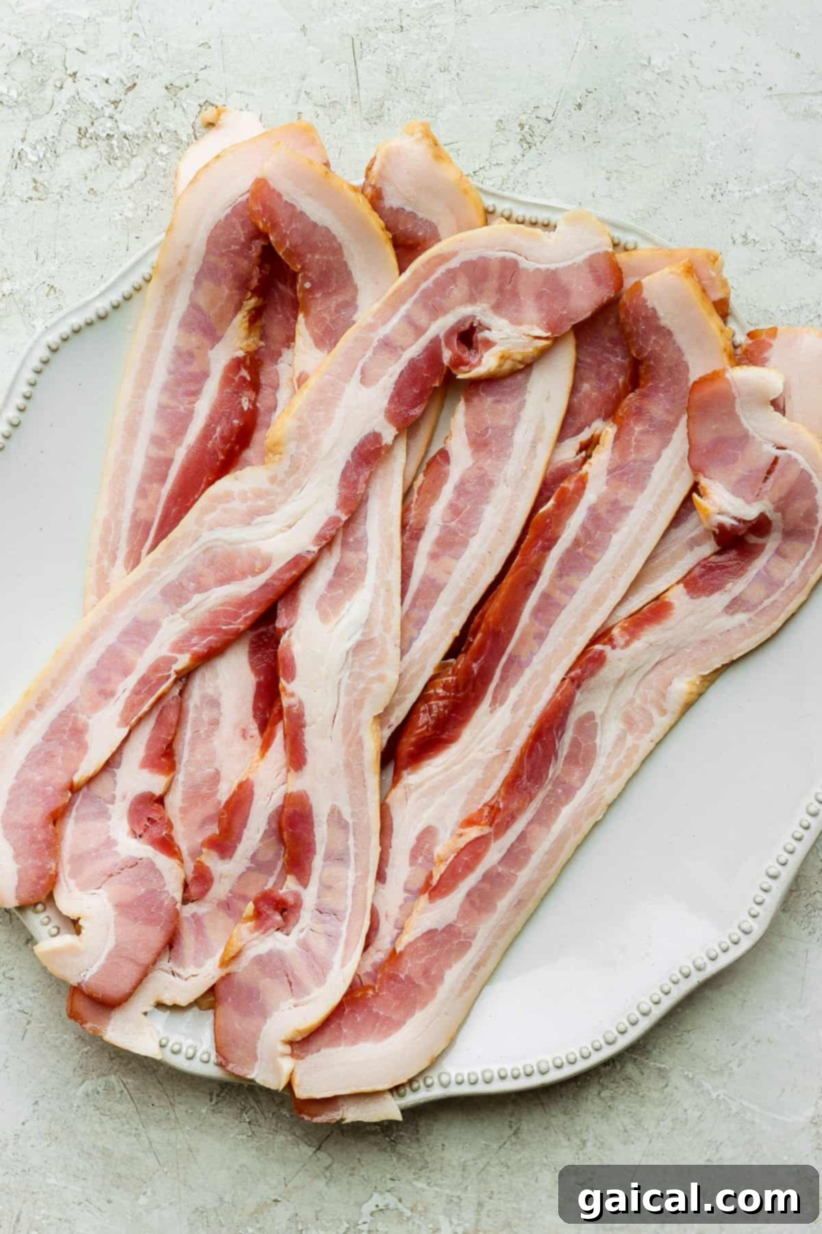 Mastering Crispy Oven Bacon 3 sliced bacon on a white plate.