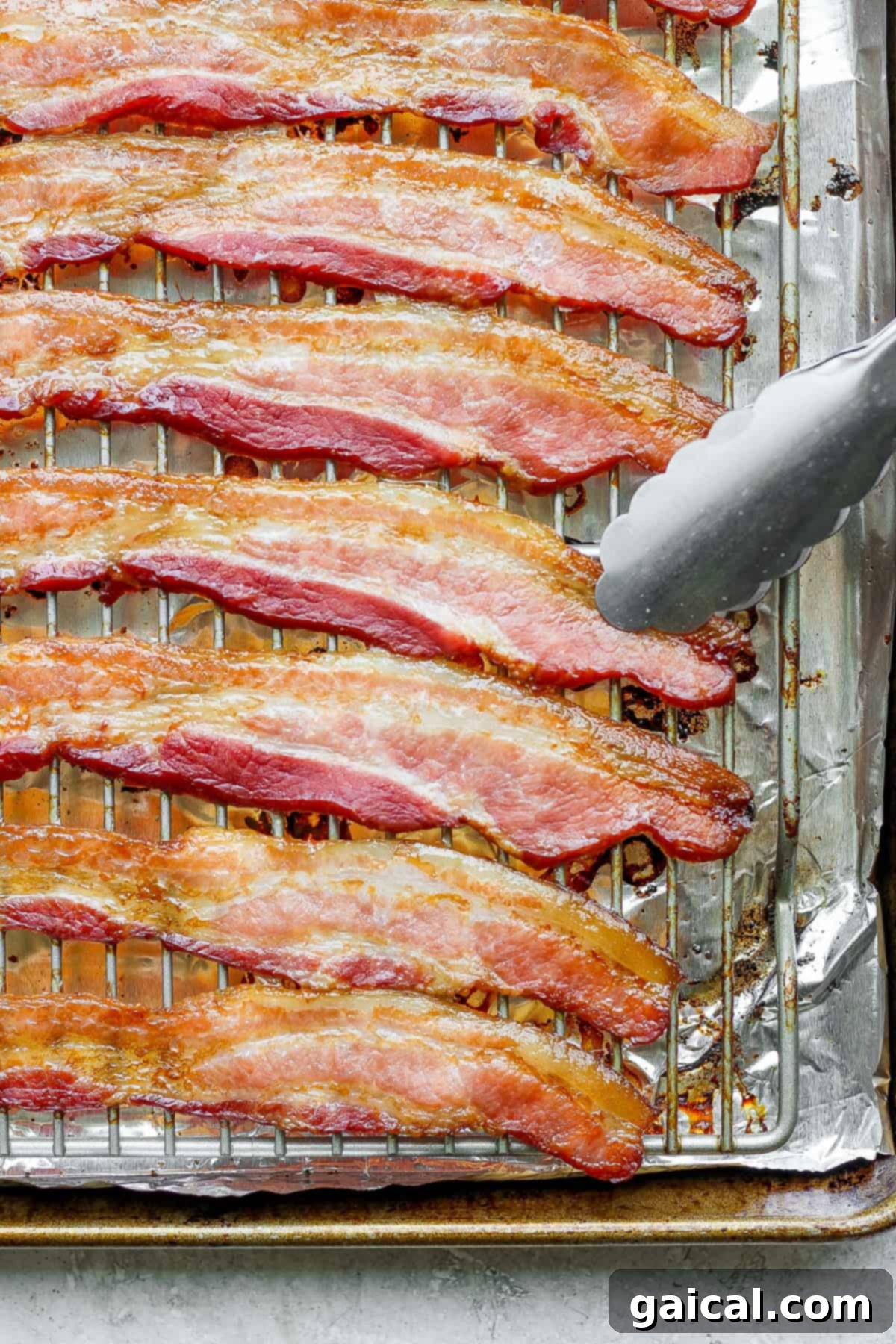 Mastering Crispy Oven Bacon 6 bacon on a baking sheet with a fork.