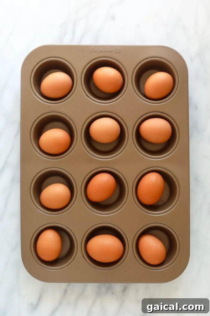 Who is a fan of hard boiled eggs? We are! There are so many ways to prepare hard boiled eggs, but making hard boiled eggs in oven is the easiest way to meal prep hard boiled eggs for breakfast, a healthy egg salad, or for an easy snack throughout the week. Let's chat about how to hard boiled eggs in the oven! Raw eggs placed in a muffin tin for baking