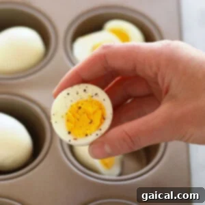 A person using an oven to hard boil eggs in a muffin tin.