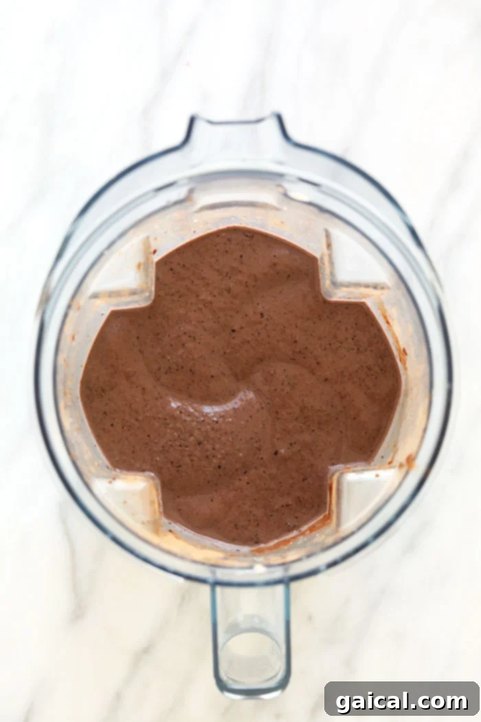 Nutrient-Rich Protein Elixir 4 A superfood protein smoothie actively blending in a high-speed blender, showing the smooth, creamy texture in progress.