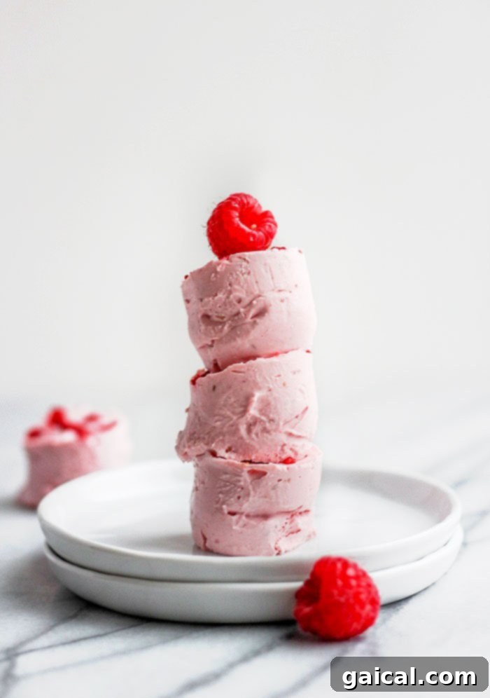 Raspberry Cheesecake Keto Truffles 2 Stacked raspberry cheesecake fat bombs with a fresh raspberry on top, showcasing a delicious keto dessert.