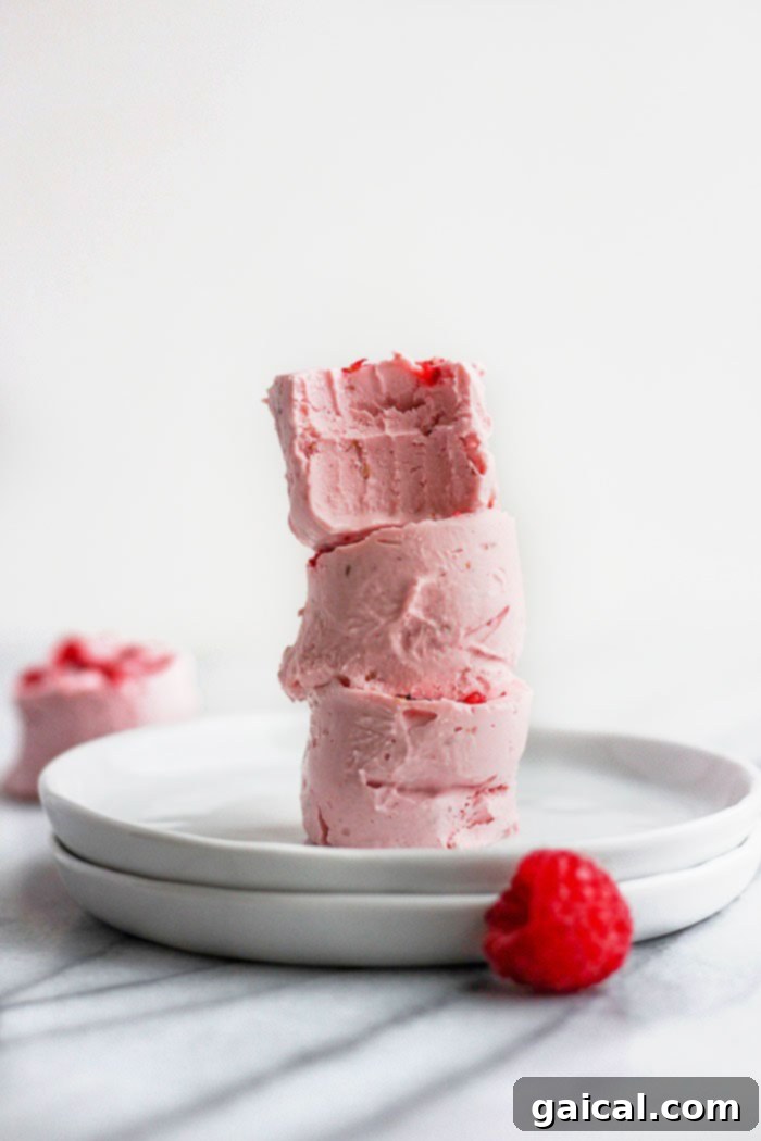 These raspberry cheesecake fat bombs are a delicious keto friendly dessert that taste just like raspberry cheesecake! Make a big batch of these fat bombs and keep them in the freezer for an easy dessert all week long. A stack of raspberry cheesecake fat bombs, one with a bite taken out, highlighting the creamy texture and inviting taste.
